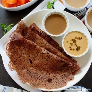 A plate of crispy ragi dosa with chutney and sambar on side
