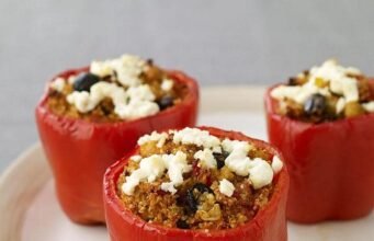 Colorful Foxtail Millet Stuffed Bell Peppers with melted cheese on top, garnished with fresh herbs.