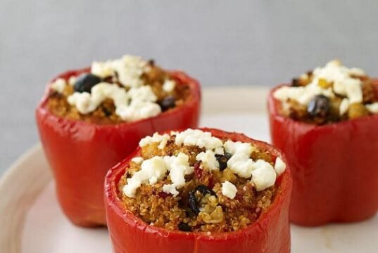 Colorful Foxtail Millet Stuffed Bell Peppers with melted cheese on top, garnished with fresh herbs.